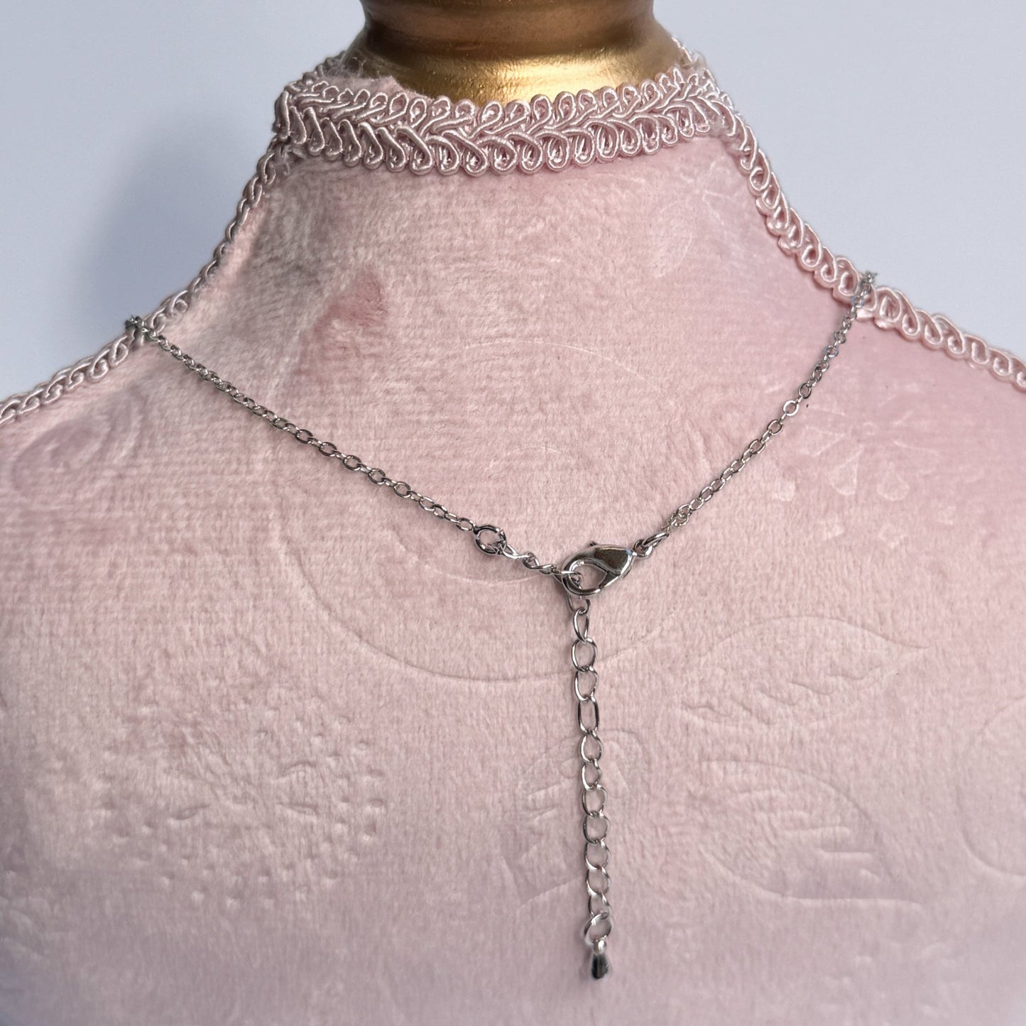 Necklace on a mannequin bust with a gold top and pink fabric