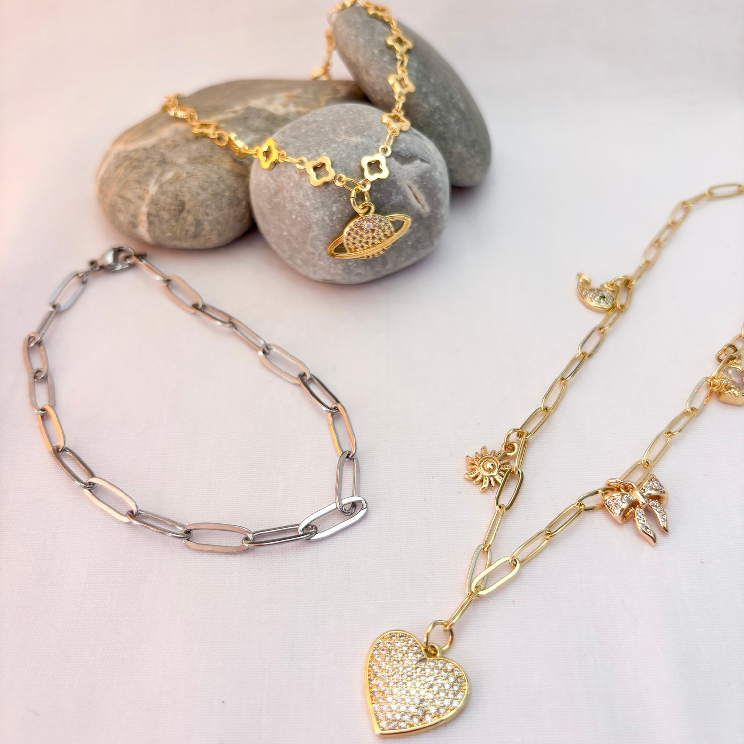 Three gold necklaces with various pendants on a light background