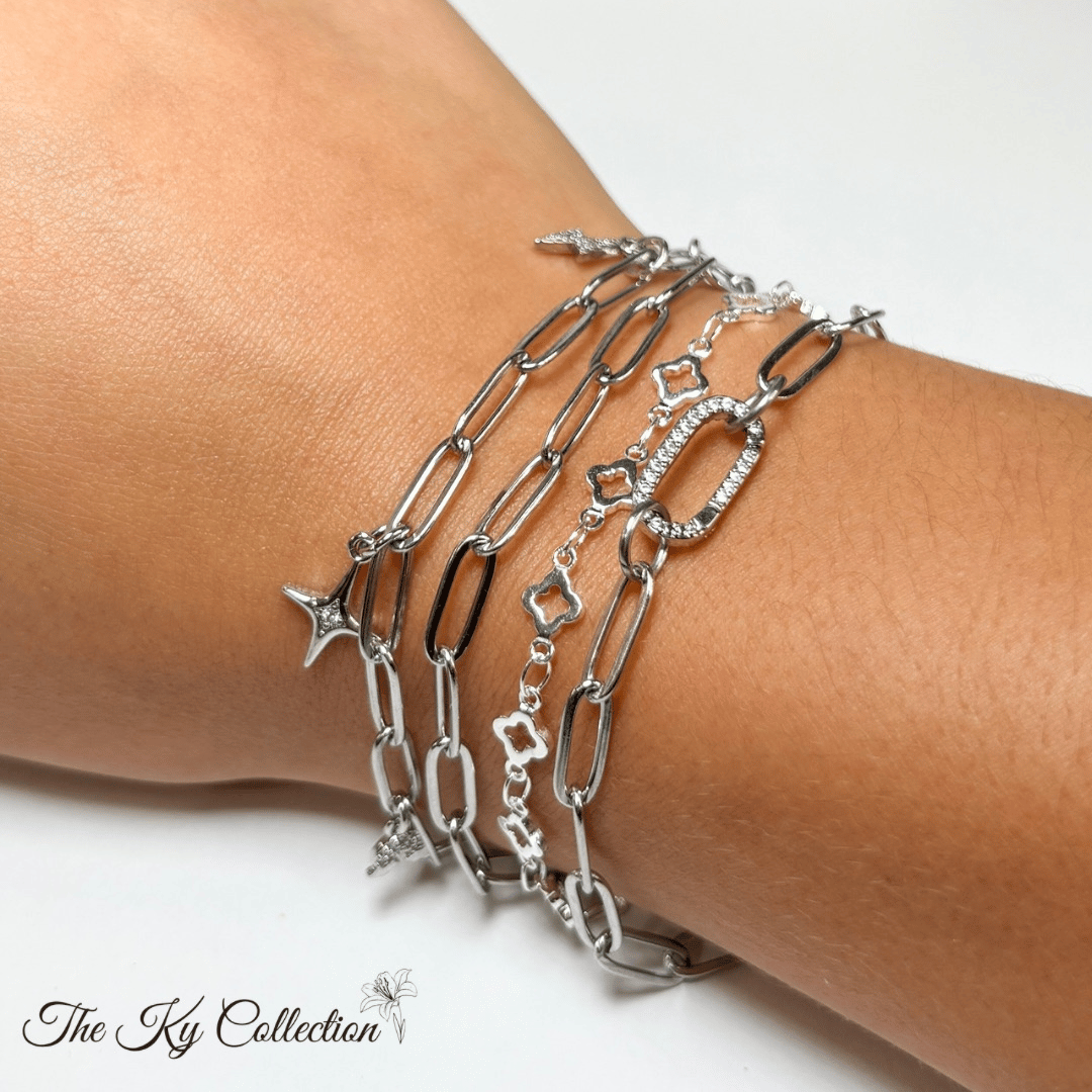 Silver chain bracelets on a wrist with 'The Ky Collection' branding.