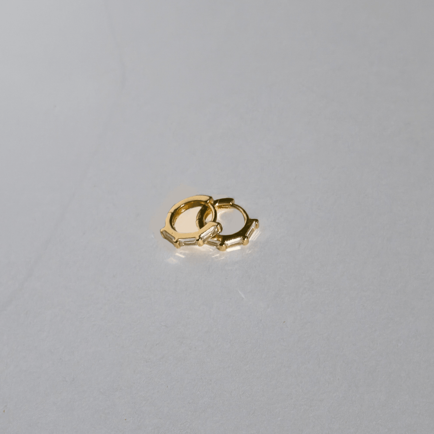 Small gold earring on a light gray background