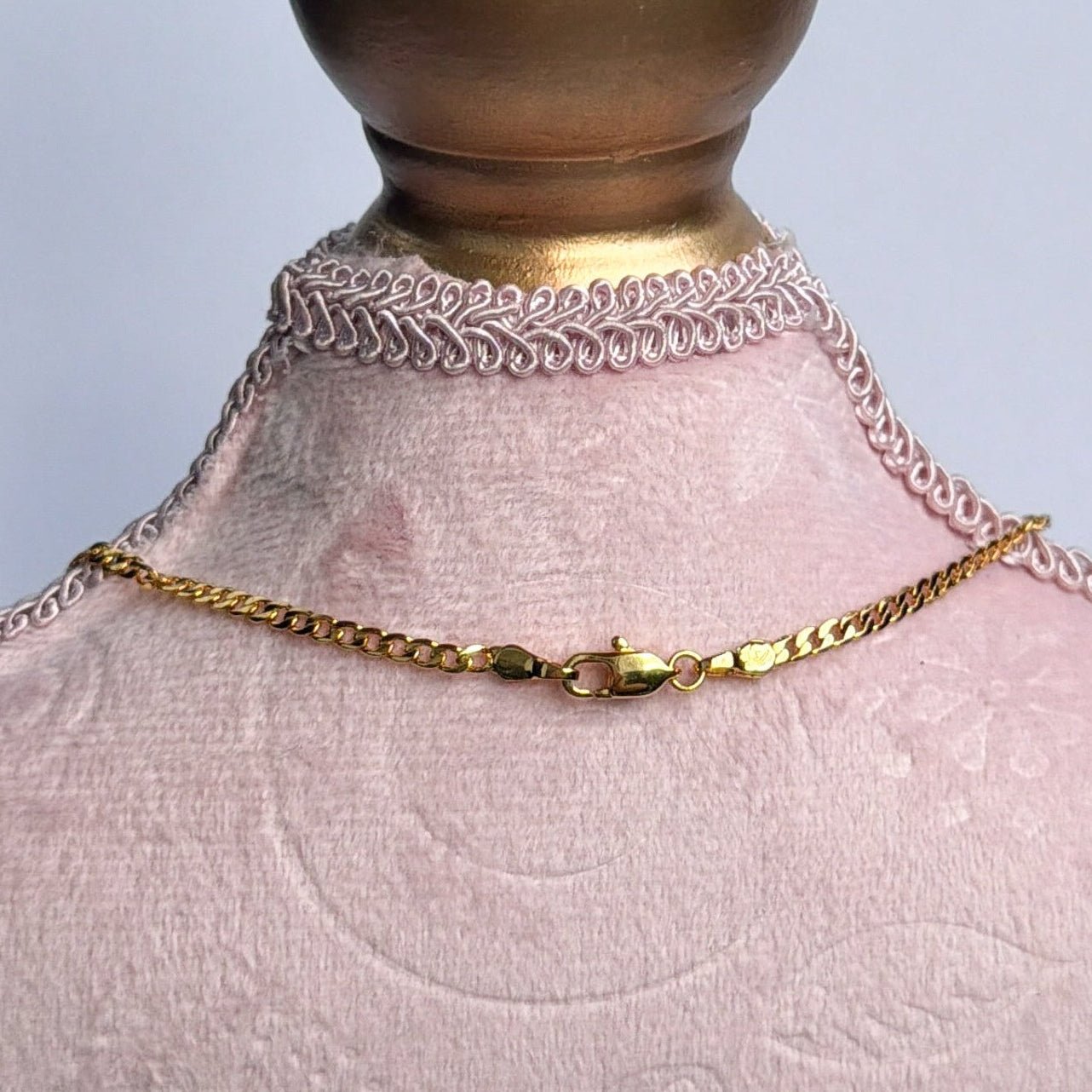 pink bust with gold necklace clasp on a light gray background