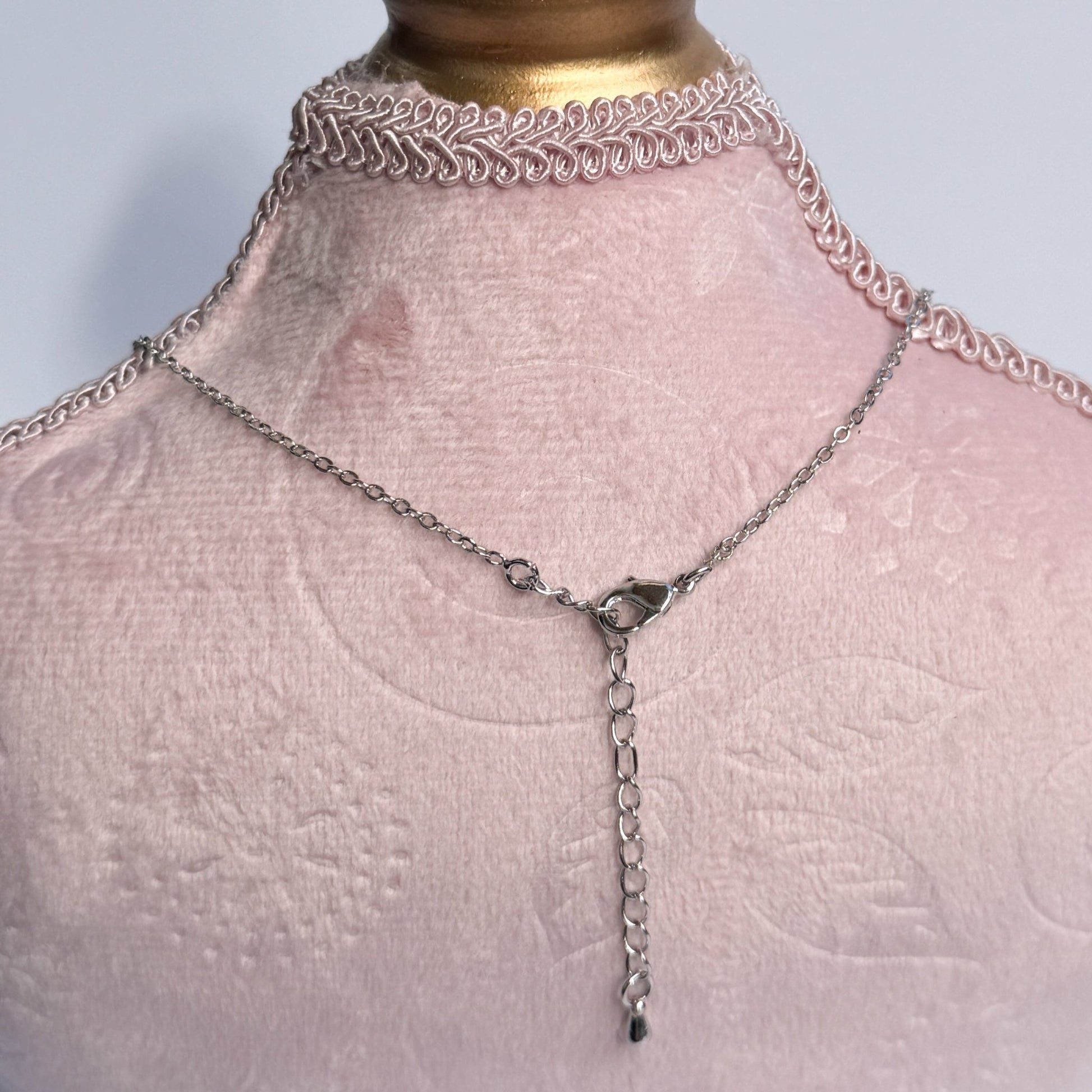 Necklace on a mannequin bust with a gold top and pink fabric